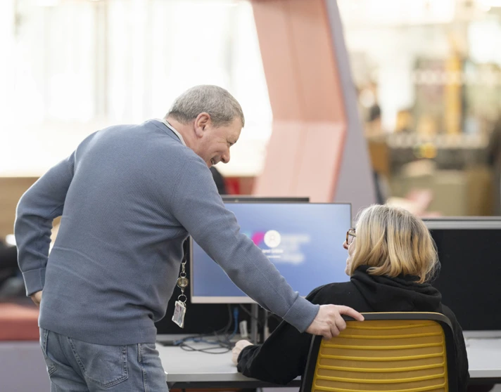 Staff member at Glasgow Kelvin College offering friendly support to a student seated at a computer in the library or learning centre. Staff member at Glasgow Kelvin College offering friendly support to a student seated at a computer in the library or learning centre.